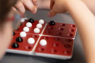 Çocuklar bir masanın etrafına oturup oyun tahtasına siyah-beyaz misketler koyarlar. Aile birlikte iyi vakit geçirmekten zevk alıyor, oyun oynayarak mutlu anılar yaratıyor. Yüksek kalite fotoğraf