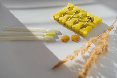 Renkli oje örnekleri, matkap uçları ve sarı ayırıcılar da dahil olmak üzere bir takım tırnak sanatları aletleri beyaz arka planda yaratıcı bir şekilde düzenlenmiştir. Doğal güneş ışığı kompozisyona sıcaklık katar.
