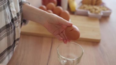 Yakın plan bir el, bir yumurtayı cam bardağa nazikçe kırıyor. Mutfaktaki basit, dokunaklı bir an. Yavaş, huzurlu ve özenli..