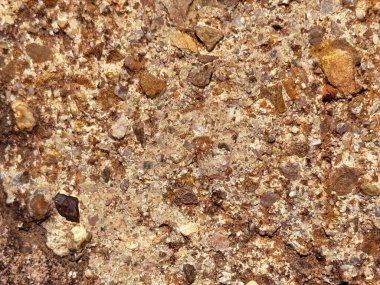 Gömülü çakıl ve mineral tanecikleriyle dolu topraksı taş dokusu, antik jeolojik katmanları ve kurak fosilleşmiş arazileri çağrıştırıyor.
