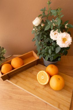 Canlı portakallar, kapalı alandaki yeşilliklerin yanında, ahşap bir tahtanın üzerinde dinleniyor, yavaş anların özünü yakalıyor, dikkatli mutfak tasarımı ve çevre dostu estetik. Bloomin ile parlak narenciye düzenleme