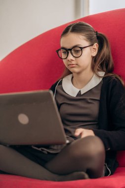 Uzaktan eğitim alan genç bir öğrenci evde dizüstü bilgisayarla çalışıyor. Düşünceli bir atmosferde disiplin teknolojisinin akıcılığını ve online derslere ve okul başarısına karşı ciddi tavırlar sergiliyor.