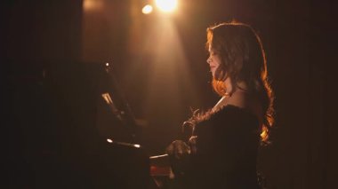Dramatik arka ışıklandırmayla aydınlatılmış, sinematik bir siluet yaratan bir piyanist. Altın parıltı performansın zarafetini ve duygusunu artırırken, ışık yansımaları rüya gibi, sanatsal bir şey ekliyor.