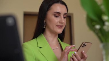 Yeşil ceketli gülümseyen bir kadın iş iletişimini, liderliği ve iletişim ağını temsil eden bir telefon görüşmesi yaptı. Şirket, danışmanlık ve uzak çalışma temaları için ideal.