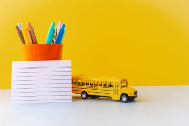 Okul otobüsü yazma araçları ve boş kart ile parlak eğitim dairesi, akademik sezonun neşeli öğrenme estetik renk uyumu organizasyonu ve asgari okul temalı kurulumunu vurguluyor