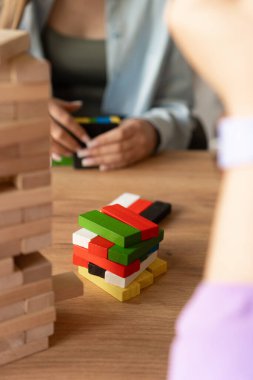 Canlı renkli bloklar, katılımcılarla çevrili ahşap bir masanın üzerinde uzanıyor. Takım oluşturma faaliyetleri, işbirliği ve yaratıcı grup dinamikleri için mükemmel bir görsel temsil.