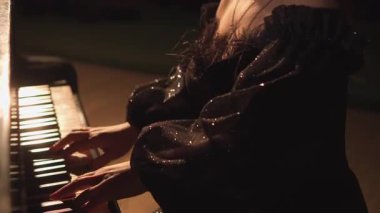 Piyanistlerin elleri loş bir atmosferde tuşların üzerinde zarif bir şekilde hareket ederek büyüleyici ve duygusal bir an yaratırlar. Sahne ışıklarının yumuşak parıltısı hareketi vurgular, derinlik ekler ve