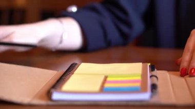 Renkli Notlu Not Defteri renkli yapışkan notlar ve kalemle yakın plan bir defter görüntüsü. Cilalanmış kırmızı tırnaklar zarafet katıyor. Çalışma alanı ya da organizasyonel tema için mükemmel.