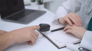 Bir doktor, yüksek teknolojili bir klinik çevreye yapılan bir hasta ziyareti sırasında dijital oksitölçer kullanarak oksijen doygunluğunu ölçer ve gerçek zamanlı sağlık veri takibi için asist tıbbi teknoloji gösterir.