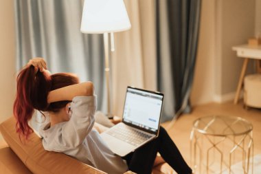 Stresli kadın, evinde dizüstü bilgisayarla oturup, dijital baskı dijital aşırı yükleme ve çağdaş çevrimiçi ekonomide uzak çalışma geleceğinin belirsizliğini temsil ederken yüzünü kapatıyor.