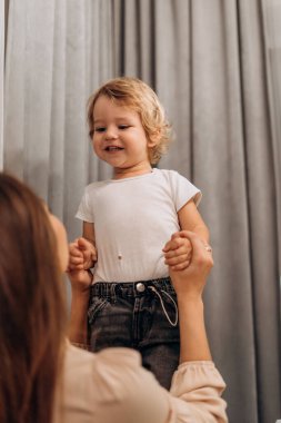 Genç bir anne, yemek masasında gülen bebeğini nazikçe kaldırır. Sıcak bir güven ve ebeveynlik gösterir. Paylaştıkları neşe, anne ve çocuğunun her gün yaşadığı bilinçli bağın özünü yakalar.
