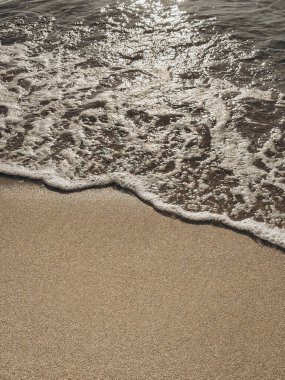 Kumlu kumsalda hafif dalgalar Minimalist kıyı şeridi manzarası yumuşak güneş ışığı altında temiz kumla buluşan doğal sakinlik kumlu sahilde hafif dalgalar, güneş ışığı üzerine yansıyor