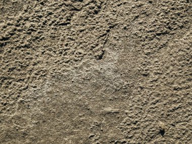 Kaba beton ya da taşa benzeyen desenli bir yüzeyin yakın plan görüntüsü, doğal toprak tonu, renk ve dokuda ince değişimler içerir..
