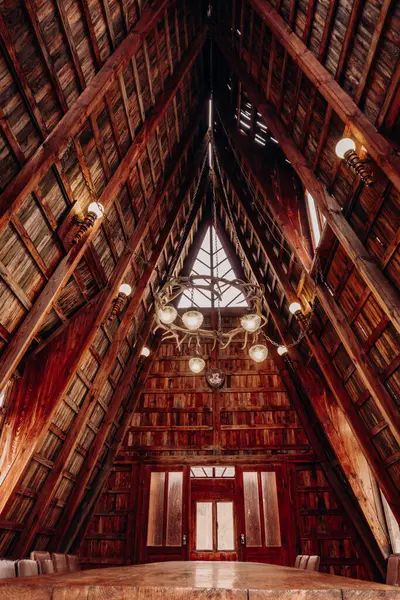 Ahşap duvarları ve tavanı olan, avizesi ve büyük ahşap bir masası olan kırsal bir kulübede..