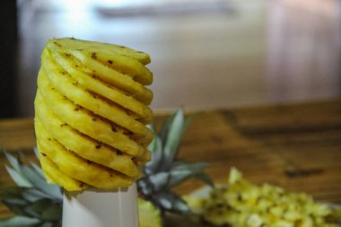 Merkezi bir çekirdek etrafında sarmal bir şekilde kesilmiş soyulmuş bir ananas, beyaz bir kaidede dimdik durur.
