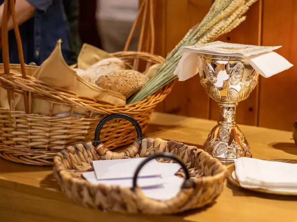 Dini bir tören sırasında sunum için hazırlanmış güzel bir masanın yakın plan görüntüsü. Bir sepetin içinde birkaç tane sade ekmek var.