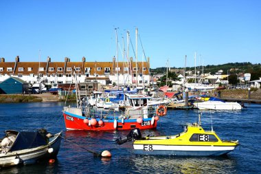 AXMOUTH, UK - 30 AĞUSTOS 2022 - Limanda nehir baltası boyunca demirlemiş balıkçı tekneleri ve yatlar ve arkada da Seaton, Axmouth, Devon, İngiltere, Avrupa, 30 Ağustos 2022.