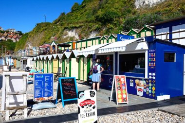 BEER, UK - 14 Temmuz 2022 - Arkasında plaj kulübeleri olan bir dondurmacıda duran çift, Bira, Devon, İngiltere, Avrupa, 14 Temmuz 2022.