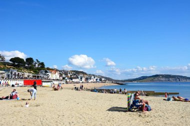 LYME REGIS, İngiltere - 21 Eylül 2022 - Kasaba binaları ile plajda dinlenen turistler ve arkada Jurassic Coast, Lyme Regis, Dorset, İngiltere, Avrupa, 21 Eylül 2022.