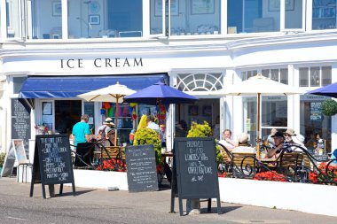 SIDMOUTH, İngiltere - 08 Ağustos 2022 - Deniz kenarındaki bir dondurmacıda dinlenen turistler, Sidmouth, Devon, İngiltere, Avrupa, 08 Ağustos 2022.
