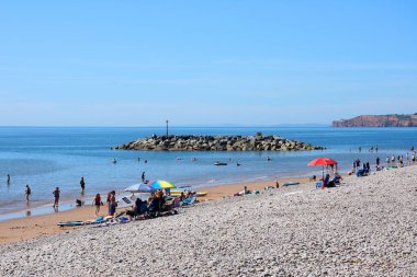 SIDMOUTH, İngiltere - 08 Ağustos 2022 - Sahilde dinlenen ve uçurumlara bakan turistler, Sidmouth, Devon, İngiltere, Avrupa, 08 Ağustos 2022.