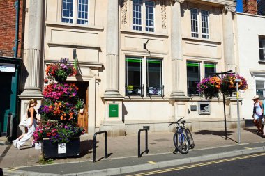 SIDMOUTH, UK - AUGust 08, 2022 - Lloyds Bank 'ın High Street boyunca ön planda güzel çiçekler ve insanlar Sidmouth, Devon, UK, Avrupa, 08 Ağustos 2022.