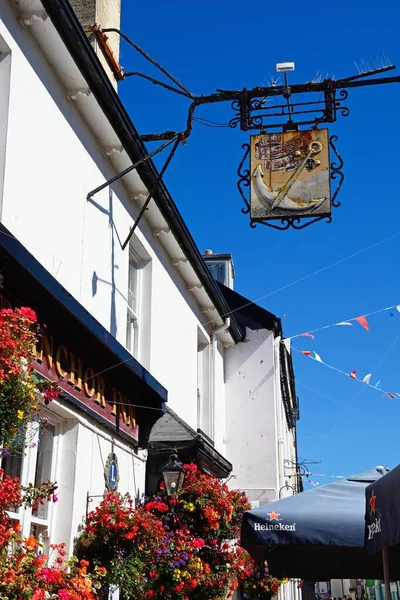 stock image SIDMOUTH, UK - AUGUST 08, 2022 - Pretty hanging baskets and pub sign on the front of the Anchor Inn along Old Fore Street in the town centre, Sidmouth, Devon, UK, Europe, August 08, 2022.