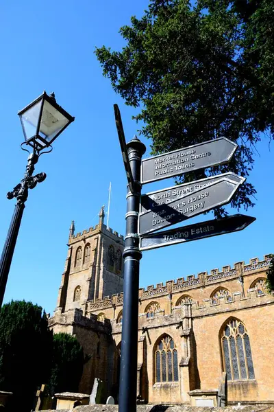 View of All Saints church along Church Street with a signpost and lamppost in the foreground, Martock, Somerset, UK, Europe,