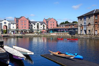 EXETER, UK - AUGUST 22, 2023 - Kayaking on the Exeter ship canal with cafes and restaurants in the Piazza Terracina to the rear and the Topsham Brewery to the right, Exeter, Devon, August 22, 2023. clipart