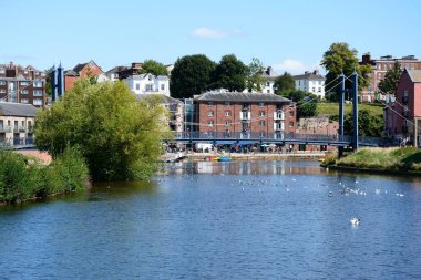 EXETER, UK - 22 AĞUSTOS 2023 - Cricklepit asma köprüsünün ön planda kuğular, arkada rıhtım restoranı, Exeter, Devon, İngiltere, Avrupa, 22 Ağustos 2023.