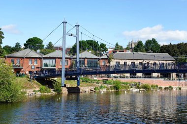 EXETER, UK - 22 AĞUSTOS 2023 - Cricklepit asma köprüsünün ön planda kuğular, arkada rıhtım restoranı, Exeter, Devon, İngiltere, Avrupa, 22 Ağustos 2023.