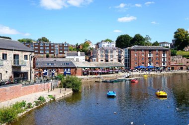 EXETER, UK - 22 AĞUSTOS 2023 - Doğu Rıhtımı boyunca mağazaları ve restoranları bulunan River Exe üzerinde pedallar üzerinde turistler, Exeter, Devon, UK, Europe, 22 Ağustos 2023.