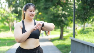 Asyalı ve cüsseli bir kadın yaz parkında dışarıda egzersiz yapıyor.