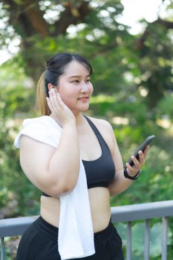 Asyalı ve cüsseli bir kadın yaz parkında dışarıda egzersiz yapıyor.