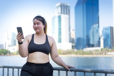  Açık havada akıllı telefon kullanan Asyalı bir kadın.