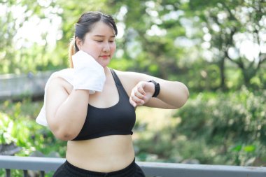 Asyalı ve cüsseli bir kadın yaz parkında dışarıda egzersiz yapıyor.