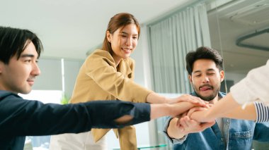 Modern ofis ortamında takım işbirliği, birlik ve destek içinde el ele tutuşmalar. Atmosfer pozitif ve takım çalışmasına odaklanmış durumda. Lider Takım Çalışması
