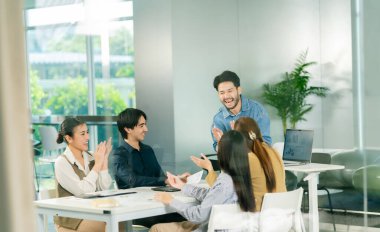 Modern ofis lideri takım çalışmasında kahkahalarla ve işbirliğiyle nişanlı takım toplantısı.