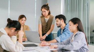 Çeşitli profesyonellerle fikir alışverişinde bulunan bir ortaklaşa iş toplantısı. Modern ofis ortamında odaklanmış takım çalışması üretkenliği ve yaratıcılığı artırır. Lider Takım Çalışması