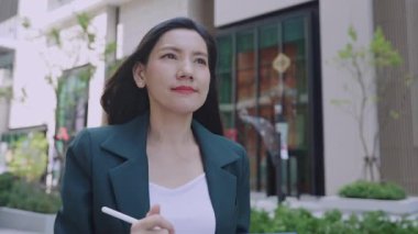 Şehir sokaklarında yürürken Stylus ve tablet kullanan ciddi bir iş kadını. 