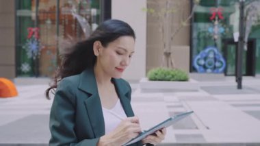 Şehir caddesinde yürürken stil ve tablet kullanan çekici bir iş kadını. 
