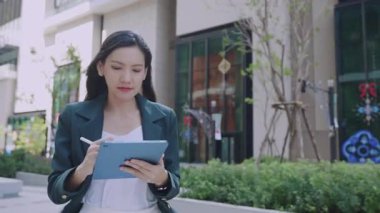 Şehir caddesinde yürürken stil ve tablet kullanan çekici bir iş kadını. 