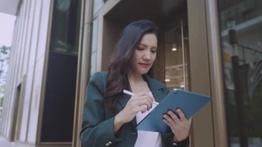 Şehir caddesinde yürürken stil ve tablet kullanan çekici bir iş kadını. 