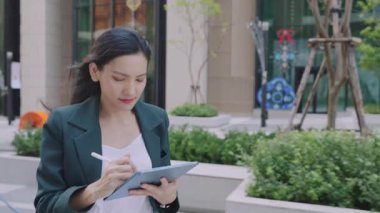 Şehir caddesinde yürürken stil ve tablet kullanan çekici bir iş kadını. 