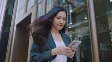 Şehir caddesinde cep telefonu kullanan takım elbiseli çekici Asyalı iş kadını. 