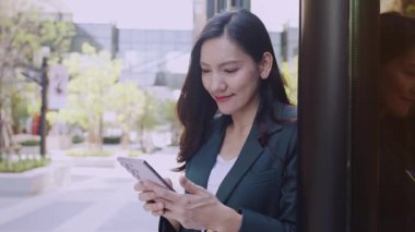 Şen şakrak iş kadını şehirde sokakta dikilirken akıllı telefondan mesaj yazıyor.