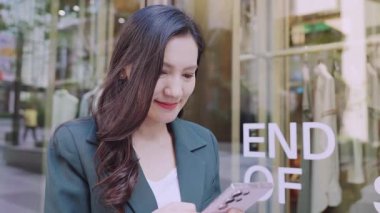 Şen şakrak iş kadını şehirde sokakta dikilirken akıllı telefondan mesaj yazıyor.