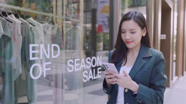 Şen şakrak iş kadını şehirde sokakta dikilirken akıllı telefondan mesaj yazıyor.