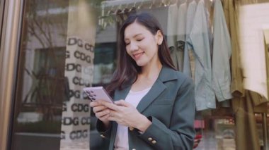 Şehir caddesinde cep telefonu kullanan takım elbiseli çekici Asyalı iş kadını. 