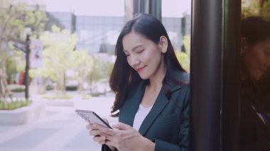 Şehir caddesinde cep telefonu kullanan takım elbiseli çekici Asyalı iş kadını. 